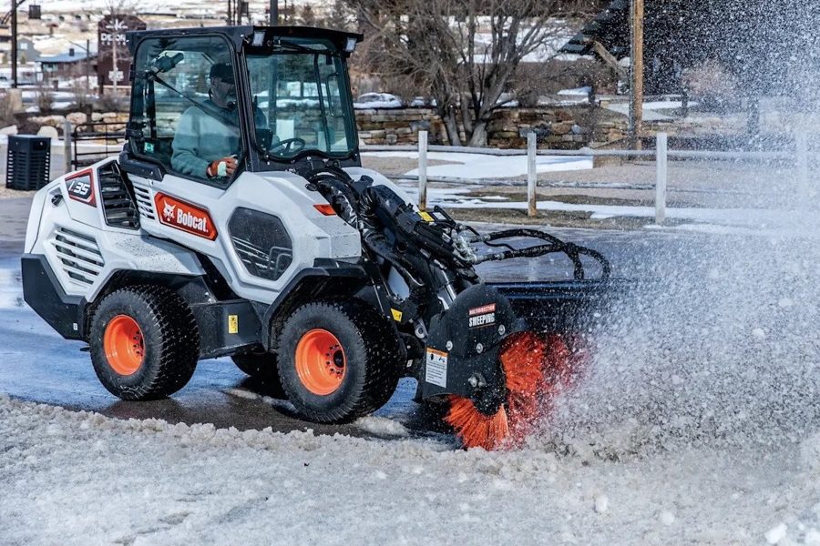 Bobcat L35 compact loader with broom attachment clearing snow